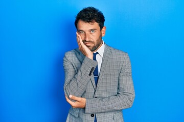 Handsome man with beard wearing business suit and tie thinking looking tired and bored with depression problems with crossed arms.