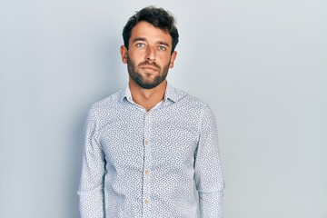 Handsome man with beard wearing casual elegant shirt with serious expression on face. simple and natural looking at the camera.