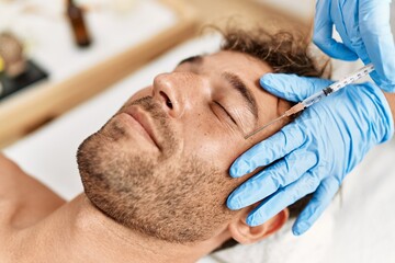 Obraz na płótnie Canvas Young hispanic man having facial anti-aging treatment at beauty center