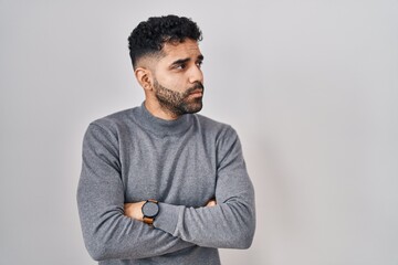 Hispanic man with beard standing over white background looking to the side with arms crossed...