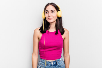 Young caucasian woman listening to music isolated on white background dreaming of achieving goals and purposes