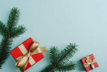 Christmas festive background. Gift boxes and fir branches on light green background. Top view, flat lay, copy space