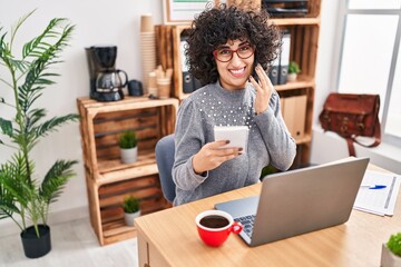 Young middle east woman business worker talking on smartphone reading notebook at office