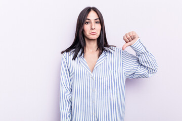 Young caucasian woman isolated on pink background showing a dislike gesture, thumbs down....