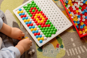 Toddler playing pegboard mosaic. Early child development. Fine motor skills. Learn and creativity
