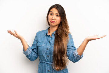 asian pretty woman shrugging with a dumb, crazy, confused, puzzled expression, feeling annoyed and...