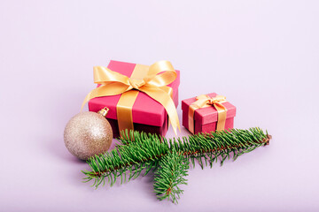 Fototapeta na wymiar Gift boxes, Christmas ball and spruce branch on light purple background. Winter holidays, festive background