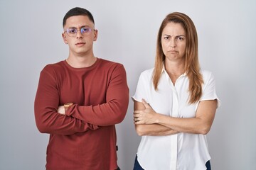 Mother and son standing together over isolated background skeptic and nervous, disapproving...