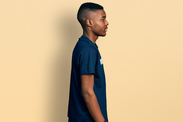 Young african american man wearing volunteer t shirt looking to side, relax profile pose with...