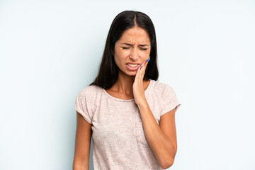 hispanic pretty woman holding cheek and suffering painful toothache, feeling ill, miserable and...