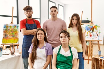 Group of five hispanic artists at art studio relaxed with serious expression on face. simple and natural looking at the camera.