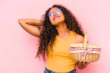 Young hispanic woman doing a picnic isolated on beige background touching back of head, thinking and making a choice.