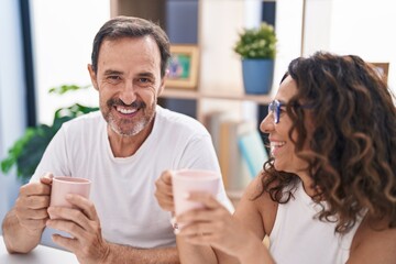 Man and woman couple drinking coffee sitting on table at home