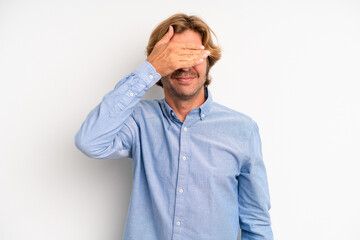 blond adult man covering eyes with one hand feeling scared or anxious, wondering or blindly waiting...