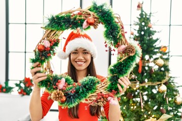 Young latin woman smiling confident holding christmas decor at home