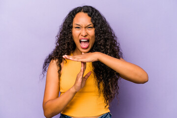 Young hispanic woman isolated on purple background showing a timeout gesture.