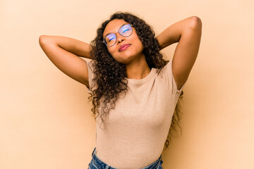 Young hispanic woman isolated on beige background feeling confident, with hands behind the head.