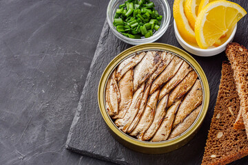 canned sprats in oil on a dark stone background