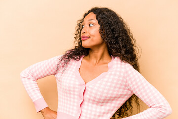 Young hispanic woman isolated on beige background dreaming of achieving goals and purposes