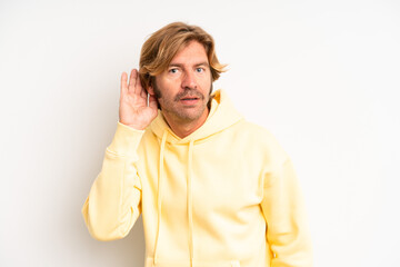 blond adult man looking serious and curious, listening, trying to hear a secret conversation or...