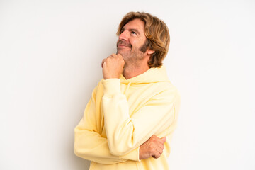 blond adult man feeling thoughtful, wondering or imagining ideas, daydreaming and looking up to...