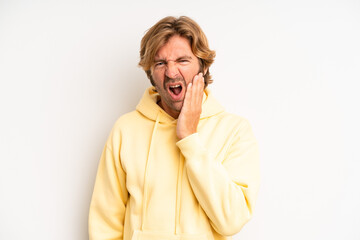 blond adult man holding cheek and suffering painful toothache, feeling ill, miserable and unhappy,...