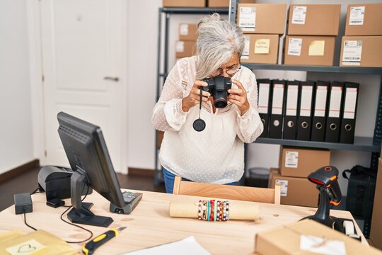 Middle age woman ecommerce business worker using professional camera at office