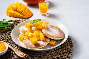 Delicious Japanese souffle pancake with dice mango and jam on white table background.