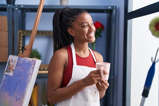 African american woman artist smiling confident drinking coffee at art studio