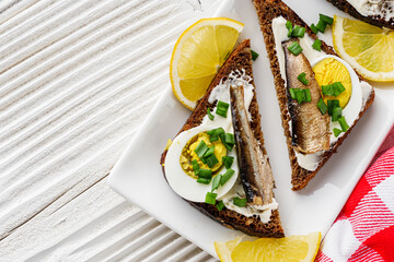 canapes with sprats on a white rustic wooden background