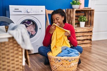 African american woman smelling towel washing clothes at laundry room