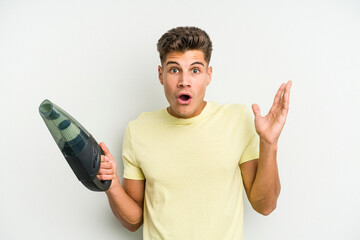 Young caucasian man holding a hand vacuum cleaner isolated on white background surprised and shocked. - Powered by Adobe