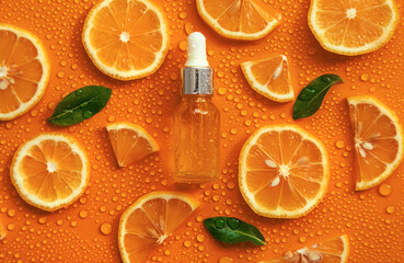 Bottle of cosmetics and drops of liquid, moisturizing orange. Hyaluronic acid. Selective focus.