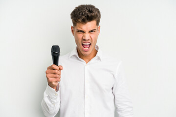 Young singer caucasian man isolated on white background screaming very angry and aggressive.
