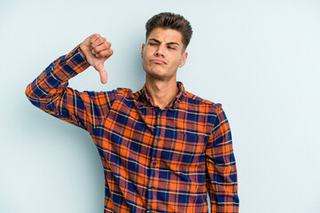 Young caucasian man isolated on blue background showing a dislike gesture, thumbs down. Disagreement concept.