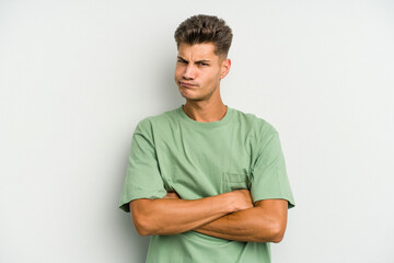 Young caucasian man isolated on white background frowning face in displeasure, keeps arms folded.