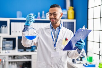 African american man scientist  holding test tube reading document at laboratory