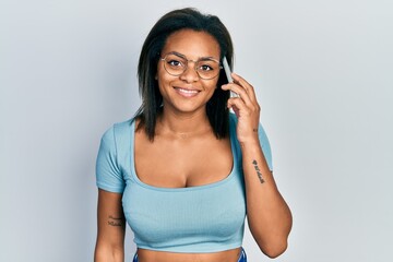 Young african american girl having conversation talking on the smartphone looking positive and happy standing and smiling with a confident smile showing teeth