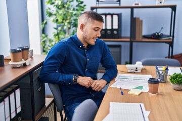 Young hispanic man business worker smiling confident sitting on des at office