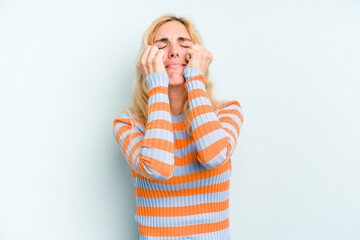 Young caucasian woman isolated on blue background crying, unhappy with something, agony and...