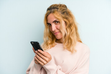 Young caucasian woman holding mobile phone isolated on blue background