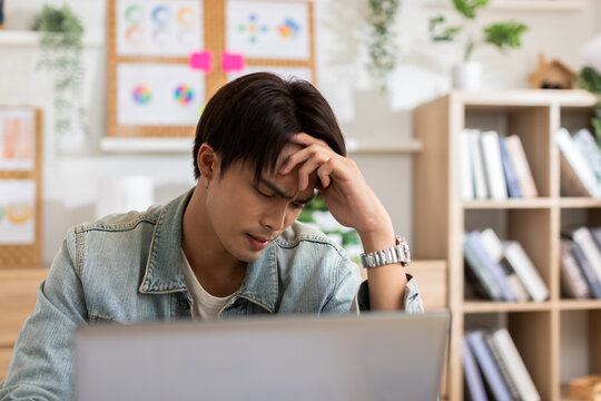Stressed Asian man suffering from a strong migraine squeezing his head. Serious man have a headache with problem of him work. eye pain problem