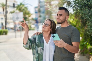 Man and woman mother and daugther using smartphone at park