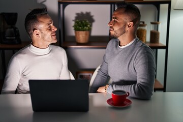 Homosexual couple using computer laptop looking to side, relax profile pose with natural face and confident smile.
