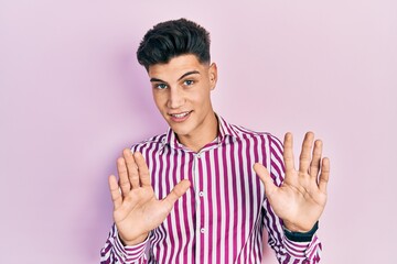 Fototapeta premium Young hispanic man wearing casual clothes moving away hands palms showing refusal and denial with afraid and disgusting expression. stop and forbidden.