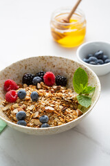 Granola with berries in a bowl for breakfast on light table