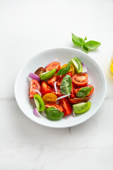 Close up of fresh summer tomatoes vegan salad with basil food in white bowl