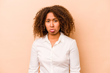Young African American woman isolated on beige background sad, serious face, feeling miserable and...