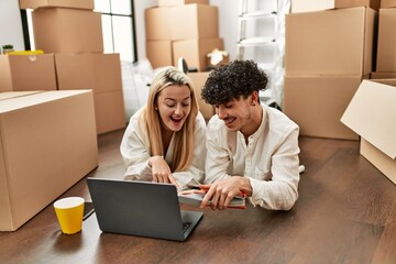 Young beautiul couple using laptop choosing painting color at new home.