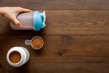 Sport shaker bottle in hands and whey protein in jar. Fitness and gym diet nutrition
